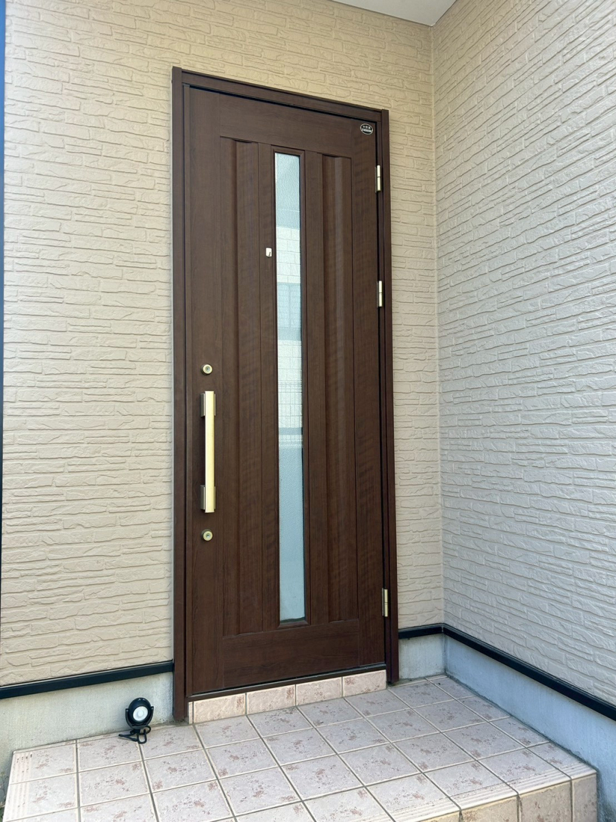 海老名市の玄関リフォーム施工前の様子。以前は断熱性の低い、濃いブラウンの古いドアが設置されていました。 海老名市の玄関リフォーム施工前の様子。以前は断熱性の低い、濃いブラウンの古いドアが設置されていました。